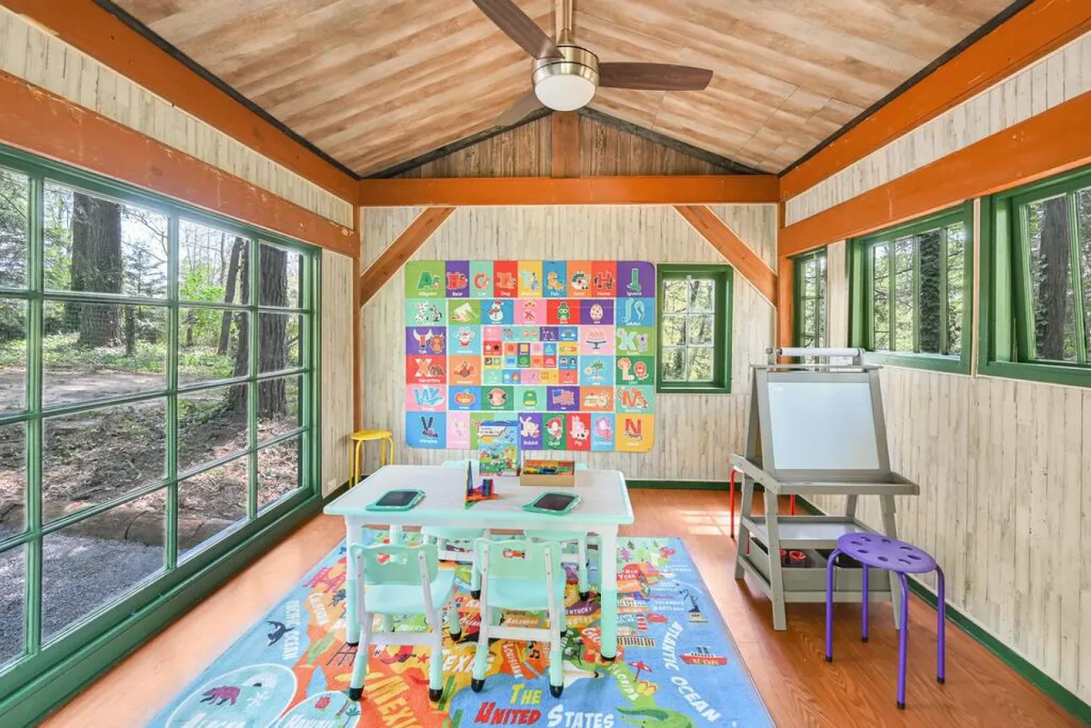 Another view of a children's creative interior space filled with colorful educational wall art, playful rugs, and child-sized furniture. The room radiates a sense of cheerfulness and is clearly set up for group play, art projects, and storytime.