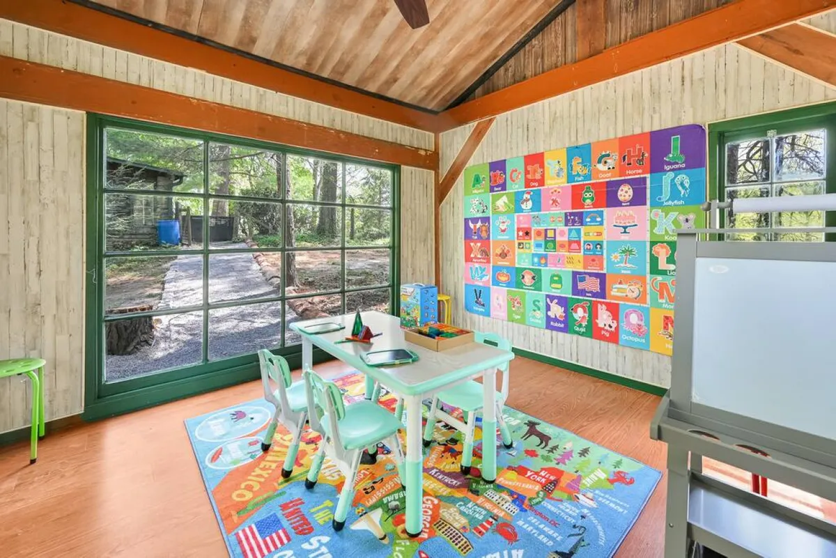 A vibrant and inviting kids' playroom featuring a child-sized table and chairs, a playful rug, and colorful wall art. A large window lets in natural light, amplifying the cheerful atmosphere. The space is tailored for creativity, with plenty of room for art and craft activities, reading, and interactive play.